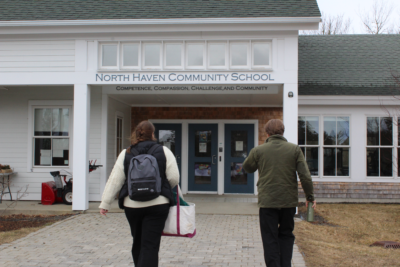 Bea Johnson, educator at ecomaine & Shaun Johnson, Principal at North Haven Community School walk side by side towards the front door of the school